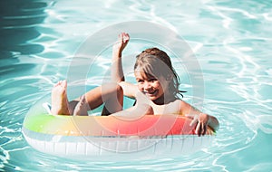 Children in swimming pool. Summer outdoor. Happy kid playing with colorful swim ring in swimming pool. Child water toys