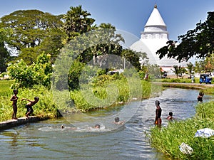 Children swimming in the river, Tissamarahama, with stupa, Sri Lanka
