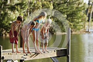 Children In Swimwear Standing On Jetty By Lake