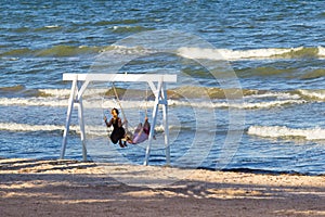 Children swing on swing by sea
