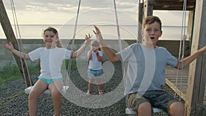 Children swing on a swing in the street at sunset.