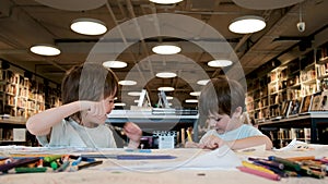 Children in t-shirts pretend fight with pencils in library