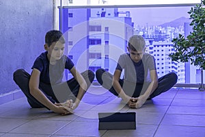 Children with tablet computer doing sport exercises, practicing yoga on balcony. Sport, healhty lifestyle, active