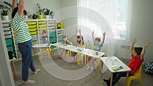 Children take turns raising their hands after completing the task.