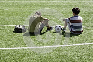 Children talking in school stadium outdoors. Teenage boy comforting consoling upset sad friend. Education, bullying