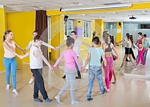 Children with teacher holding hands and dancing in dance school