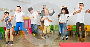 Children with teacher jumping together in schoolroom