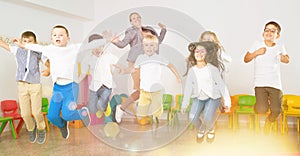 Children with teacher jumping together in schoolroom photo