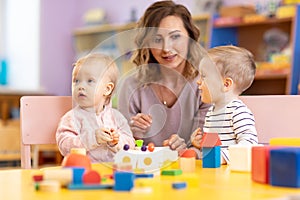 Children with teacher playing educational toys, stacking and arranging colorful pieces. Learning through experience concept, gross