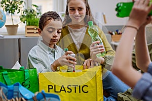 Children with teacher separating rubish in to three bins.