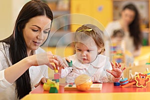 Children with teachers play with color wooden puzzle in a montessori classroom