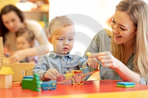 Children with teachers play with color wooden puzzle in a montessori classroom