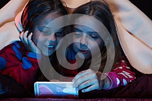 Children and technology concept. Girls with curious faces looking at phone screen