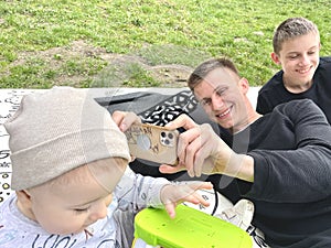 Children and a teenager play taking pictures on the phone while resting in the park