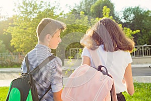 Children teenagers go to school, back view. Outdoors, teens with backpacks