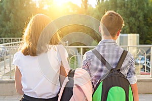 Children teenagers go to school, back view. Outdoors, teens with backpacks