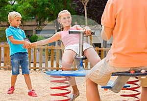 Children are teetering on the swing in the playground.