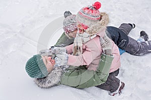 Children with their father in winter clothes, playing in a snowdrift on the street.  Happy family spend time outdoors in winter