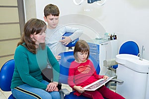 Children with their mother are looking at a dental X-ray in a dentistÃ¢â¬â¢s clinic photo