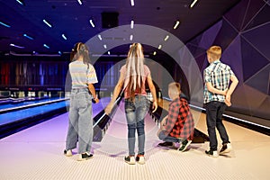 Children throw a ball on the lane in bowling alley