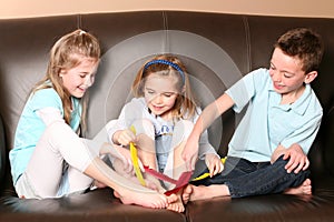 Children tickling feet with feather