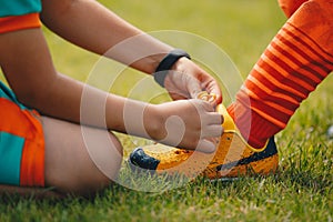 Children tie shoelaces at grass sports field