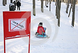 Children are tobogganing near prohibiting sign