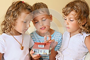 Children together keeping in hands model of house