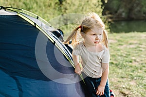 Children tourism. Kid girl in a campaign in a tent. Family summer vacation in nature