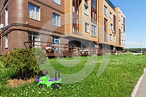 Children toys in grass near house building exterior mixed-use urban multi-family residential district area sunny summer