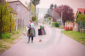 Children in traditional folk costumes complimenting on Easter with colorful spring decoration with eggs