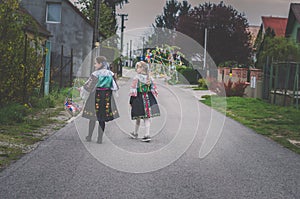 Children in traditional folk costumes complimenting on Easter with colorful spring decoration with eggs