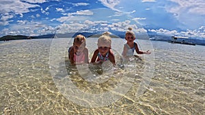 Children of the Triplet Sister play on the beach and in shallow water