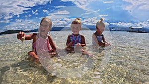 Children of the Triplet Sister play on the beach and in shallow water