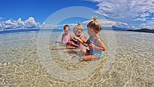 Children of the Triplet Sister play on the beach and in shallow water