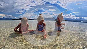 Children of the Triplet Sister play on the beach and in shallow water