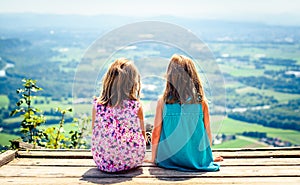 Children - twin girls sitting on paragliding ramp after hiking.