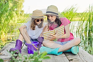 Children two girls resting playing reading their notebook in nature