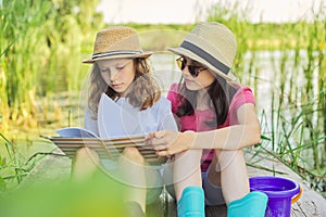 Children two girls resting playing reading their notebook in nature