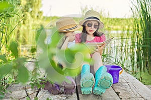 Children two girls resting playing reading their notebook in nature