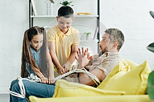 children tying scared father with rope