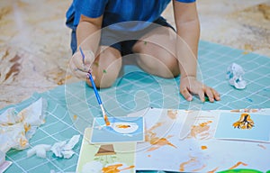 Children use paintbrushes to paint watercolors on paper to create their imagination and enhance their learning skills.