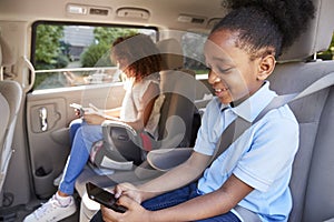 Children Using Digital Devices On Car Journey