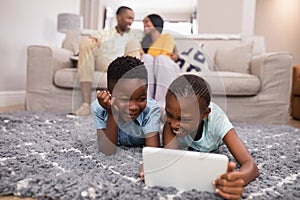 Children using digital tablet while parents siting on sofa at home