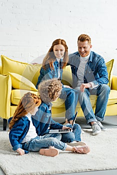 Children using laptop while parents sitting