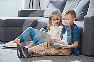 children using laptop and sitting on floor