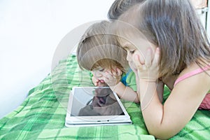 Children using tablet lying on bed at home. Children time spending. Kids using tablet