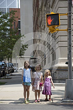 Children wait to cross street at stop signal