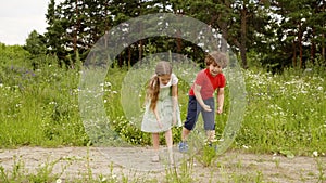 Children walk and play on flower meadow tear flowers at summer outdoor activity.