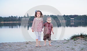 Children walk together on the bank of the lake. Active family walk